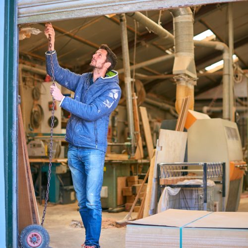 Carpenter Opening Door To Woodwork Business Premises At Start Of Working Day