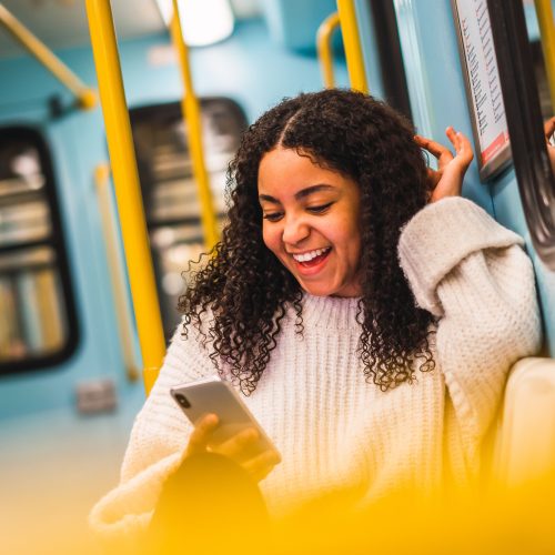 Smiling black woman using smartphone in transport
